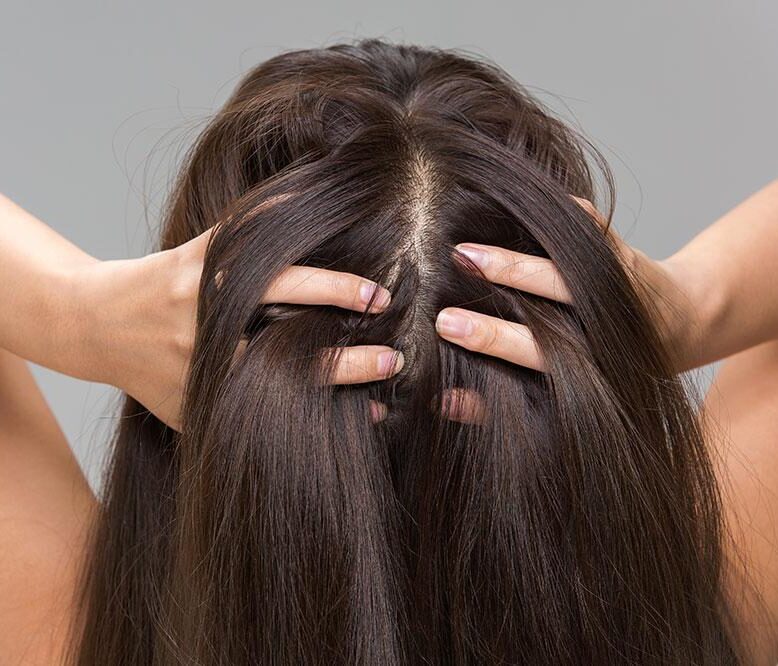 Woman gently checking her scalp and hair