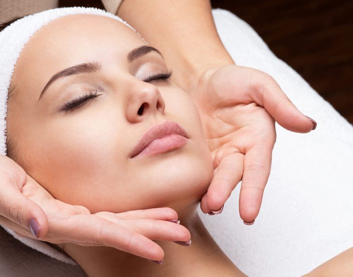 Masseur doing massage the head of an adult woman in the spa salon