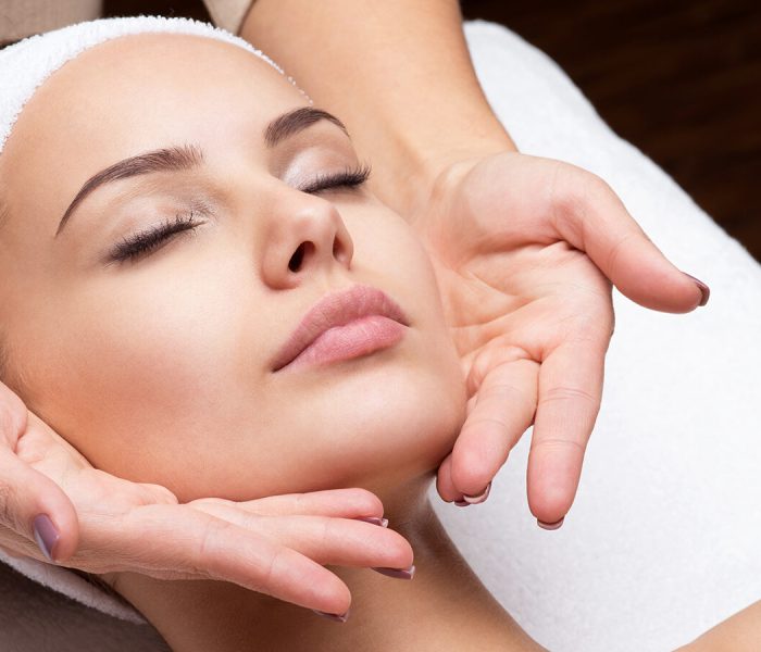 Masseur doing massage the head of an adult woman in the spa salon